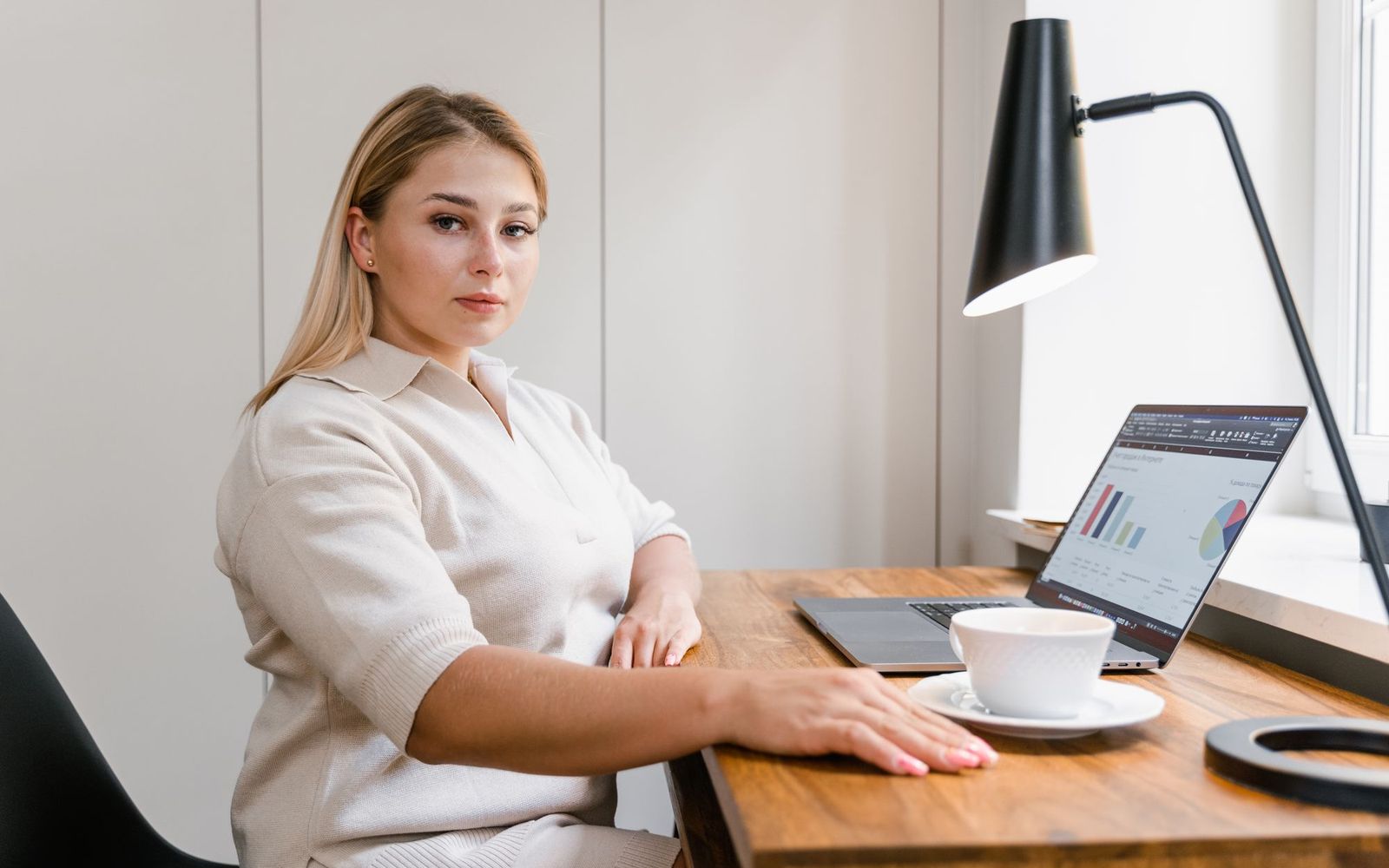 A freelancer working at a kitchen table with a laptop and a notebook
