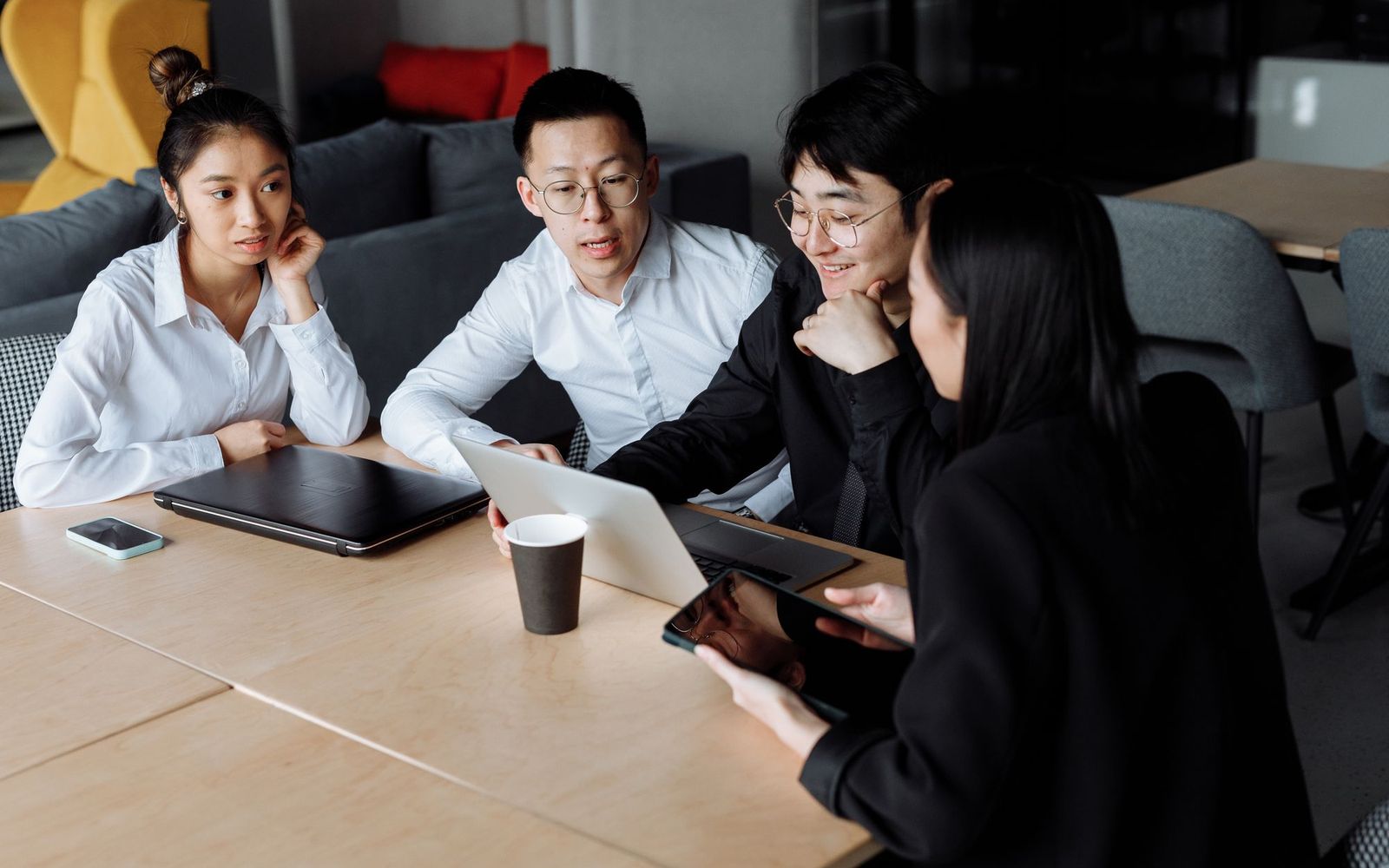 Two colleagues talking across a table in a small meeting room
