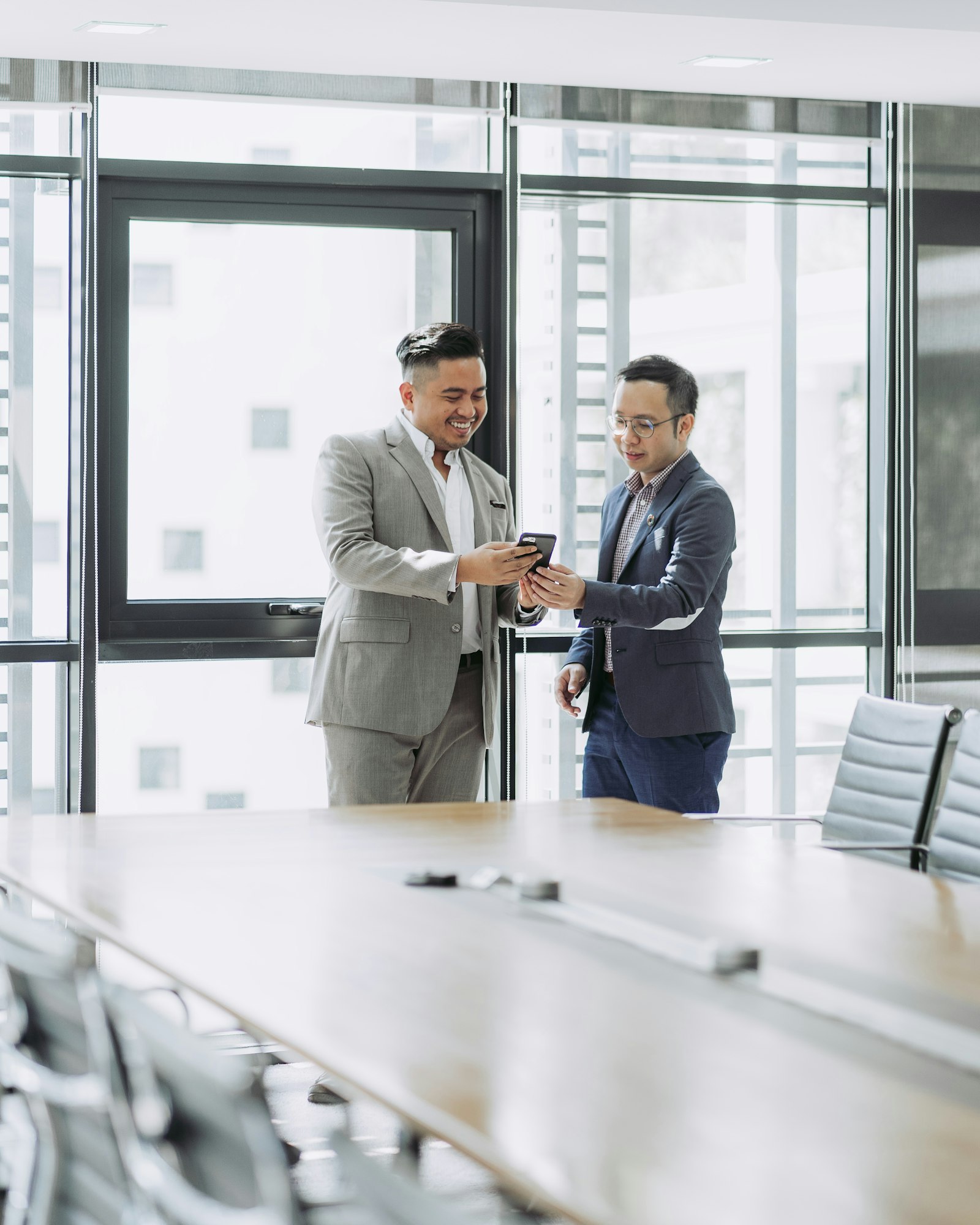 Two colleagues looking at a phone together in an office